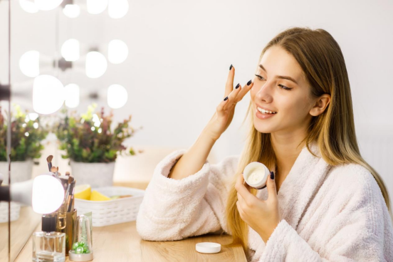 A beautiful woman sitting at the dressing table applying skin care products